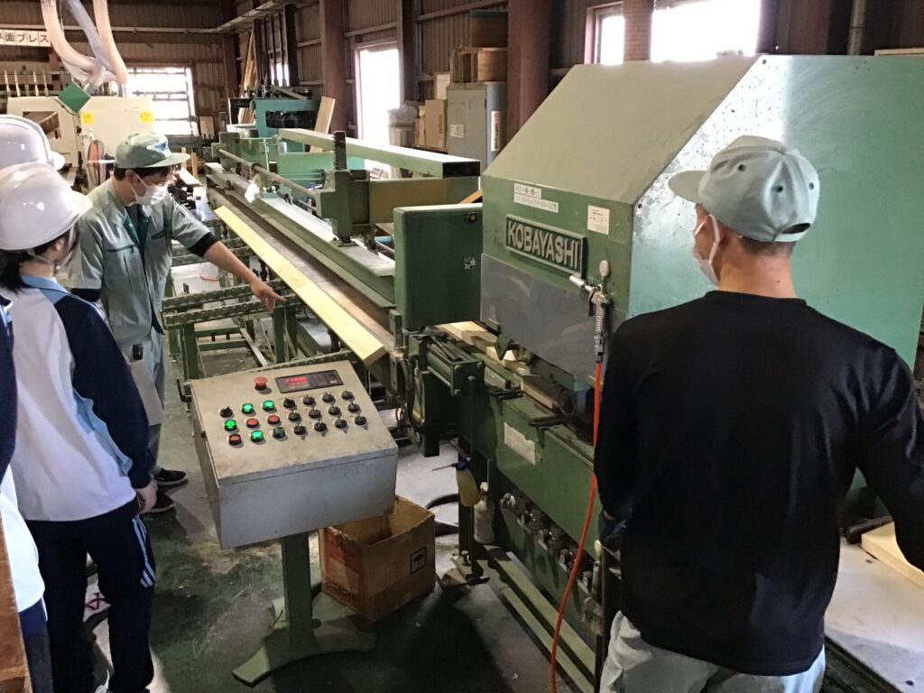 TSC工場見学風景　集成材を圧着する機械を見学しているところ