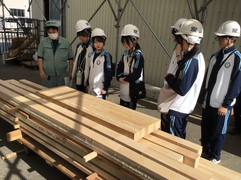 TSC工場見学風景　集成材の圧着が終わり、研磨と指定された寸法に加工される荷台を見学しているところ